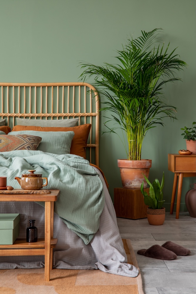 sypialnia boho zielona z dodatkami i rośliną 